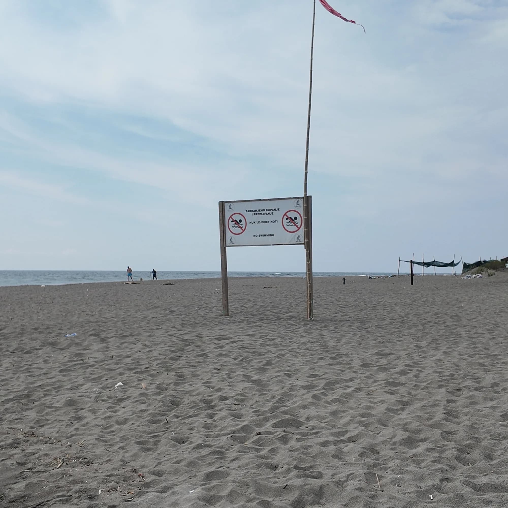 A flag and a sign at the entrance to the beach on Ada Bojana