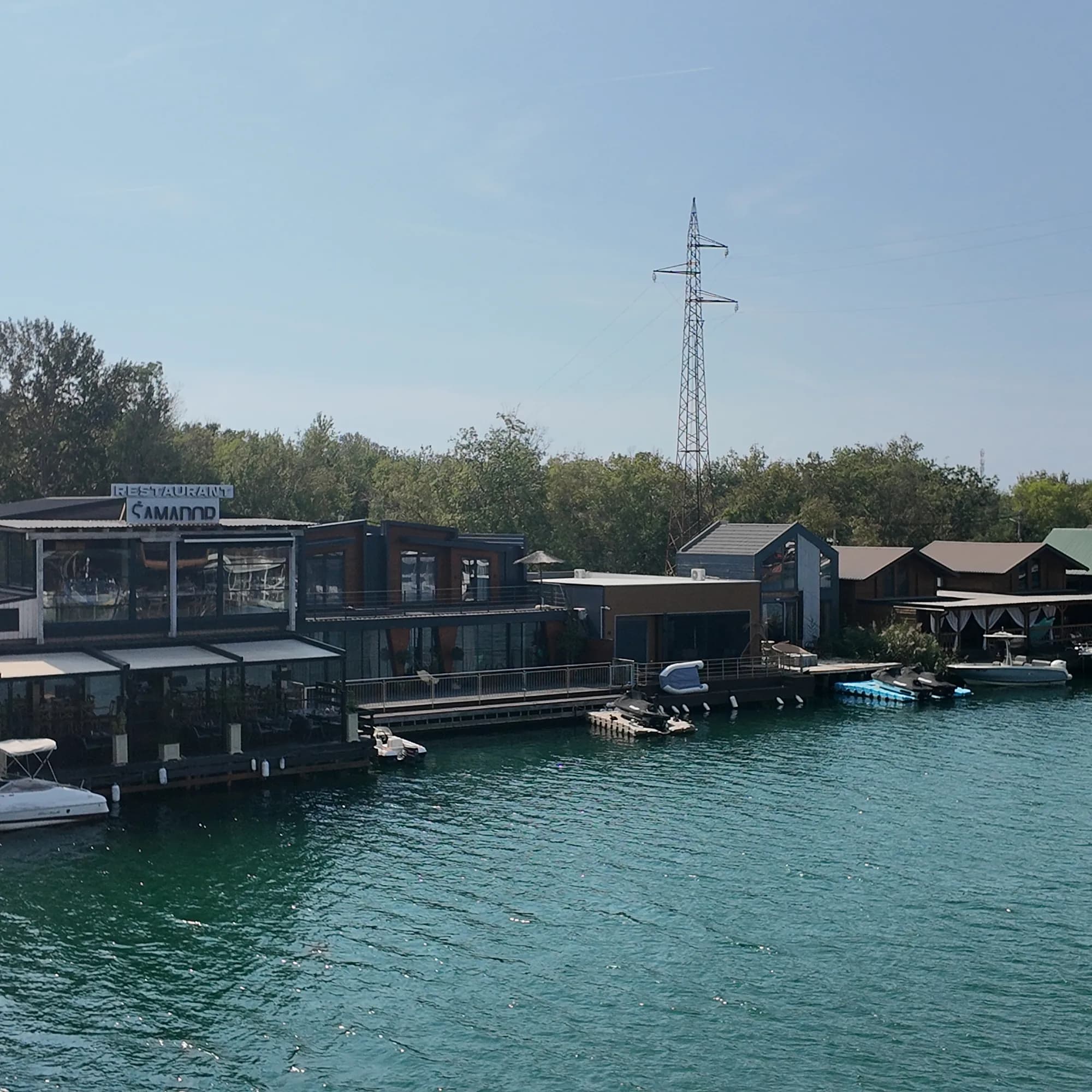 Wooden houses and restaurants on piles over the river arm at Ada Bojana