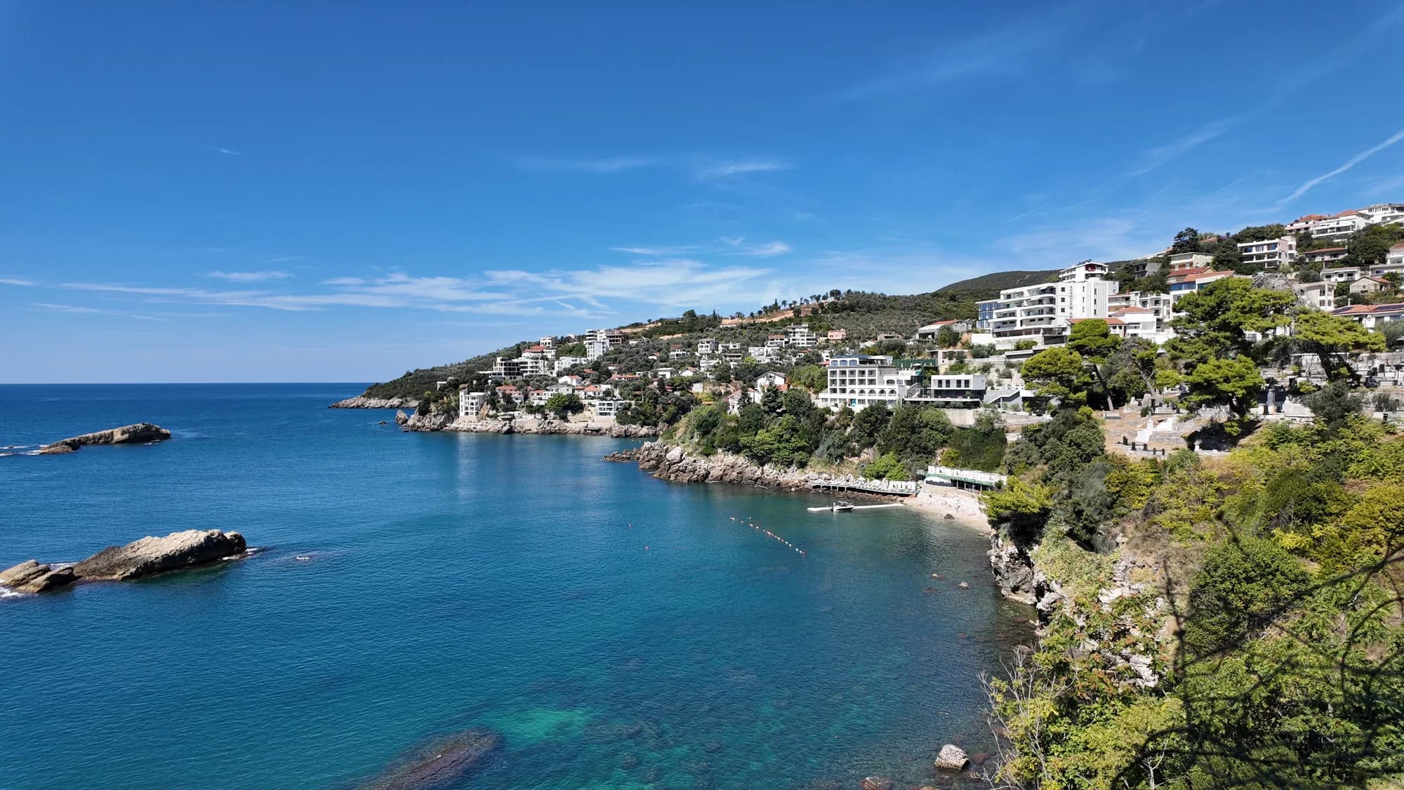 The rocky coast below the Old Town walls, villas on the slope and clear water over the reef