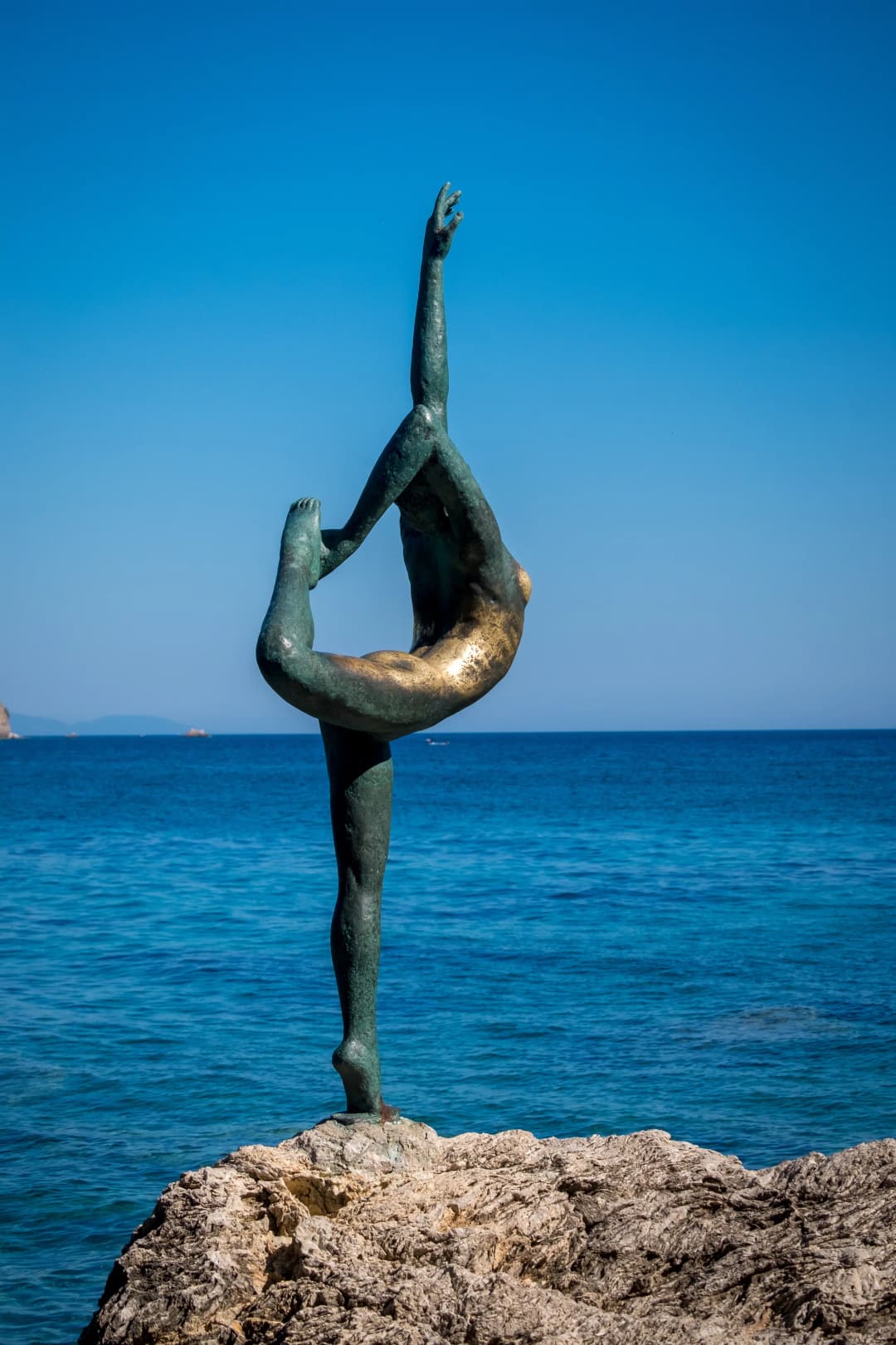 Close-up of the Ballerina statue of Budva, its bronze worn to gold where visitors touch it for luck