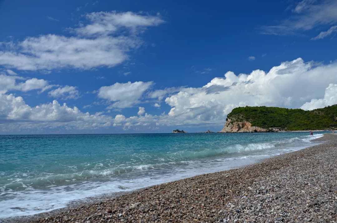 The empty pebble shore of Buljarica looking toward the wooded headland