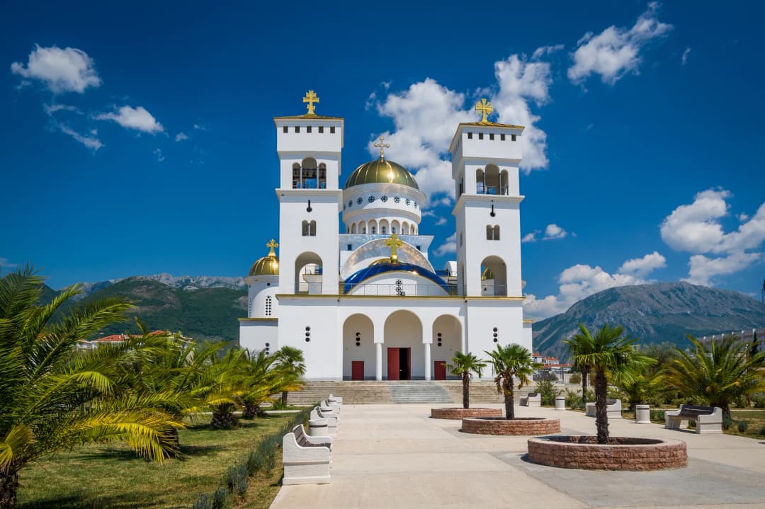 White facade and golden domes of the Cathedral of Saint Jovan Vladimir in Bar with Rumija mountains behind