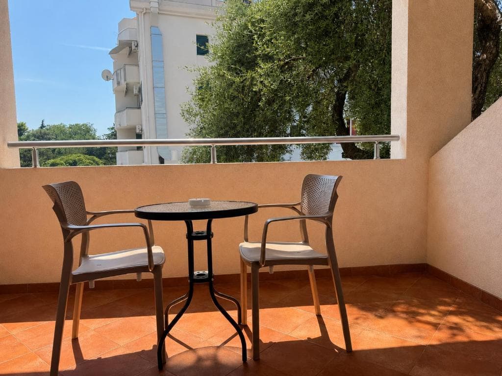 Balcony with table and chairs overlooking olive trees at Lyon Apartmani Budva