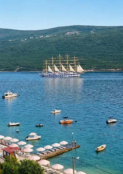 A tall ship anchored in the bay off the Kumbor beach umbrellas