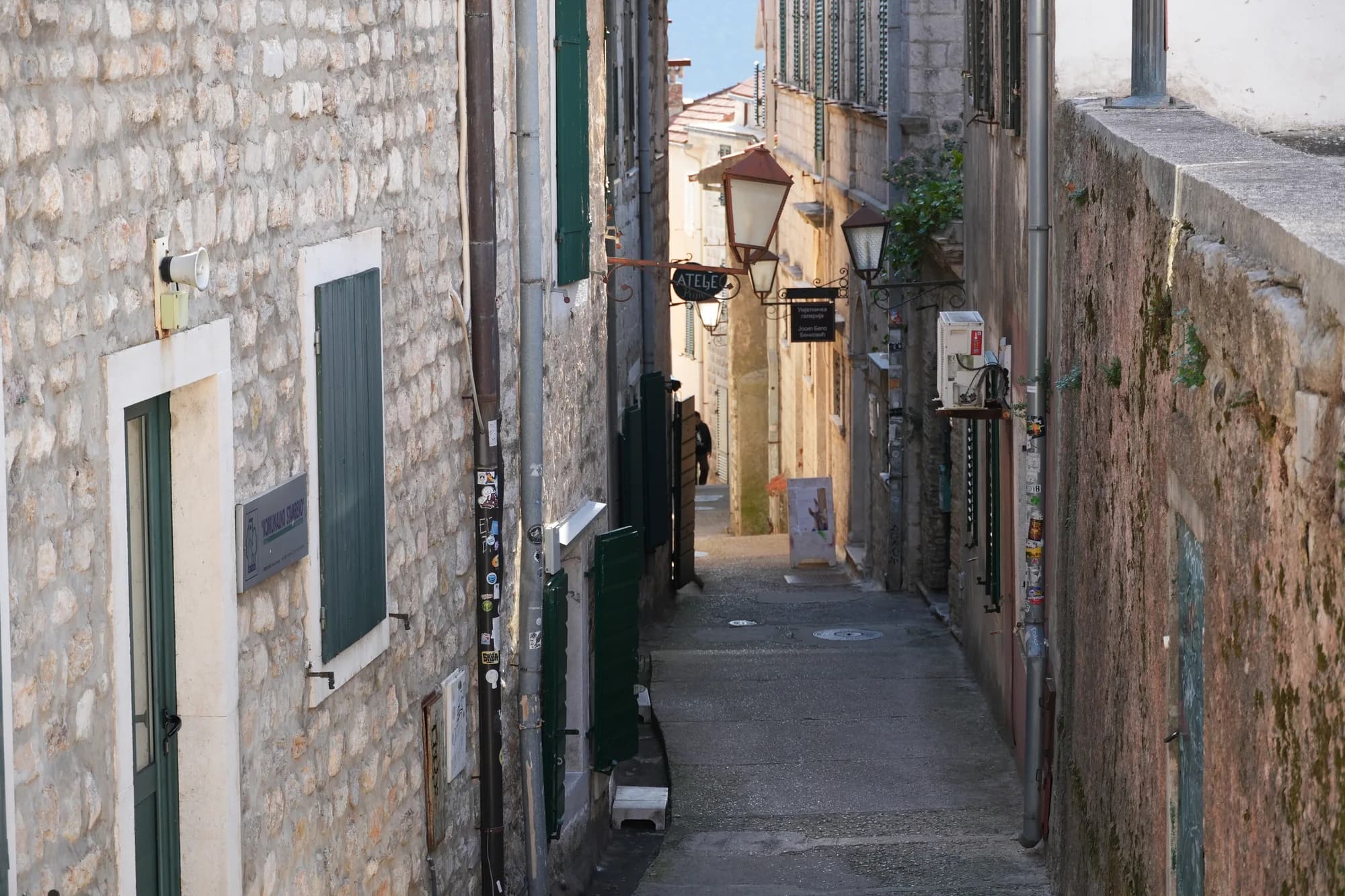 Una estrecha escalera de piedra que desciende entre casas con contraventanas cerradas del casco antiguo