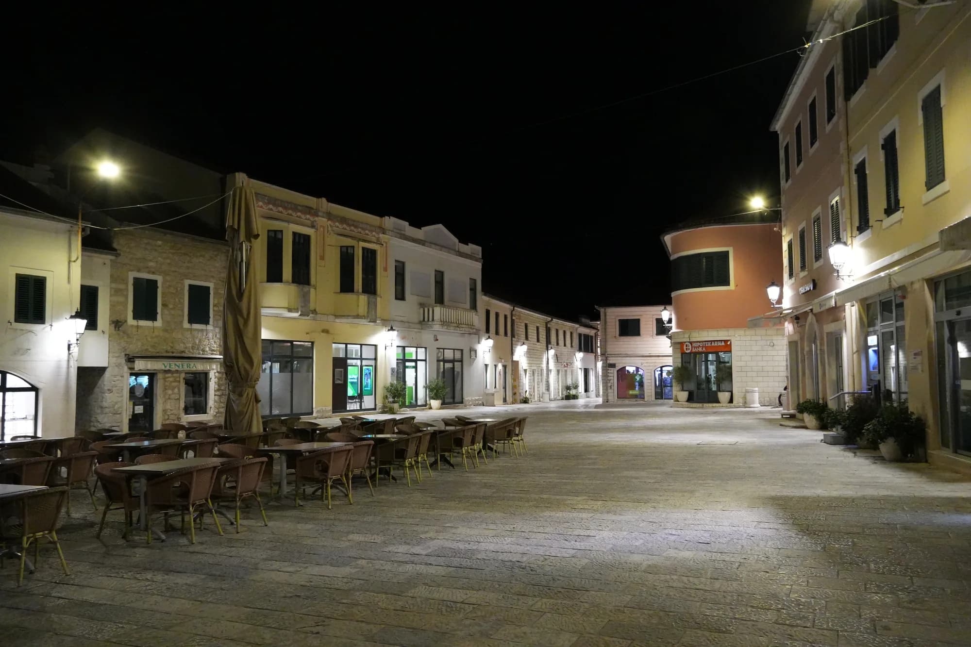 Terrazas de cafés vacías en la plaza Nikola Đurković de noche