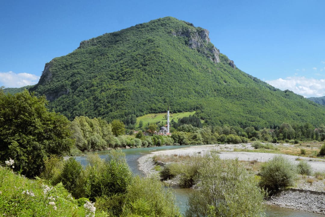 River valley with a mosque below a wooded limestone slope in the Bijelo Polje region