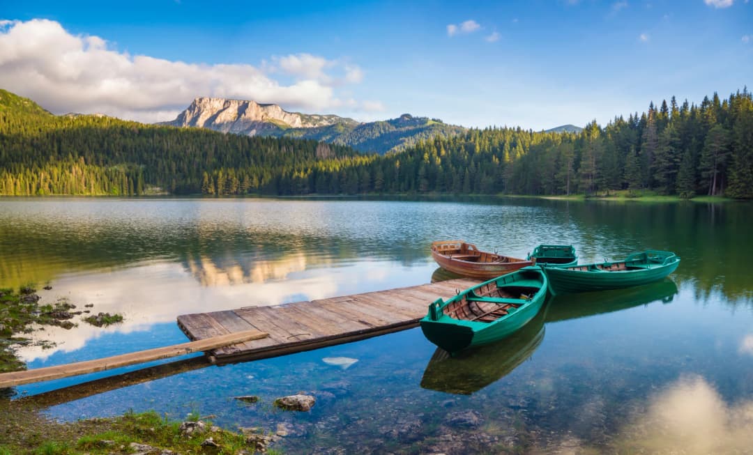 Wooden boats moored on Black Lake beneath forest and Durmitor cliffs