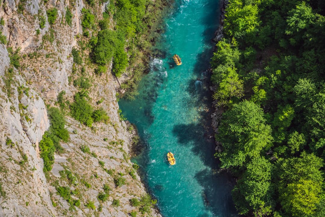 A raft carrying paddlers through whitewater on a fast mountain river