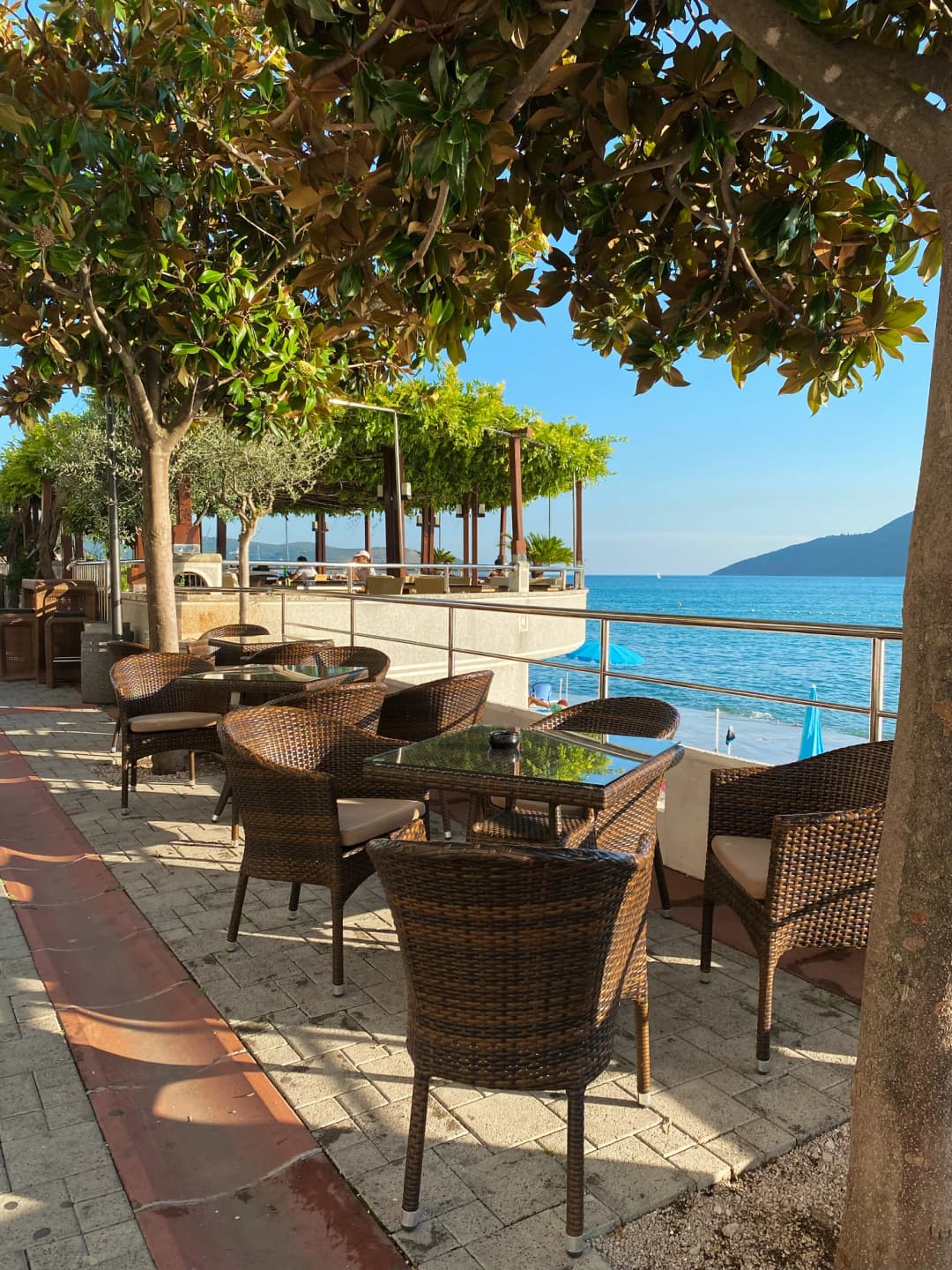 Paseo marítimo de Herceg Novi con terrazas de restaurantes con vistas a la bahía y fortaleza al fondo