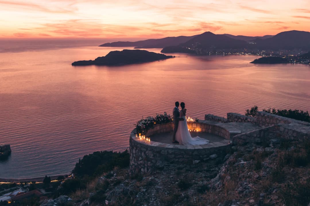 Una ceremonia civil en curso en una oficina municipal de Montenegro, o alternativamente, una pareja firmando el registro con una vista de la Bahía de Kotor a través de la ventana detrás de ellos