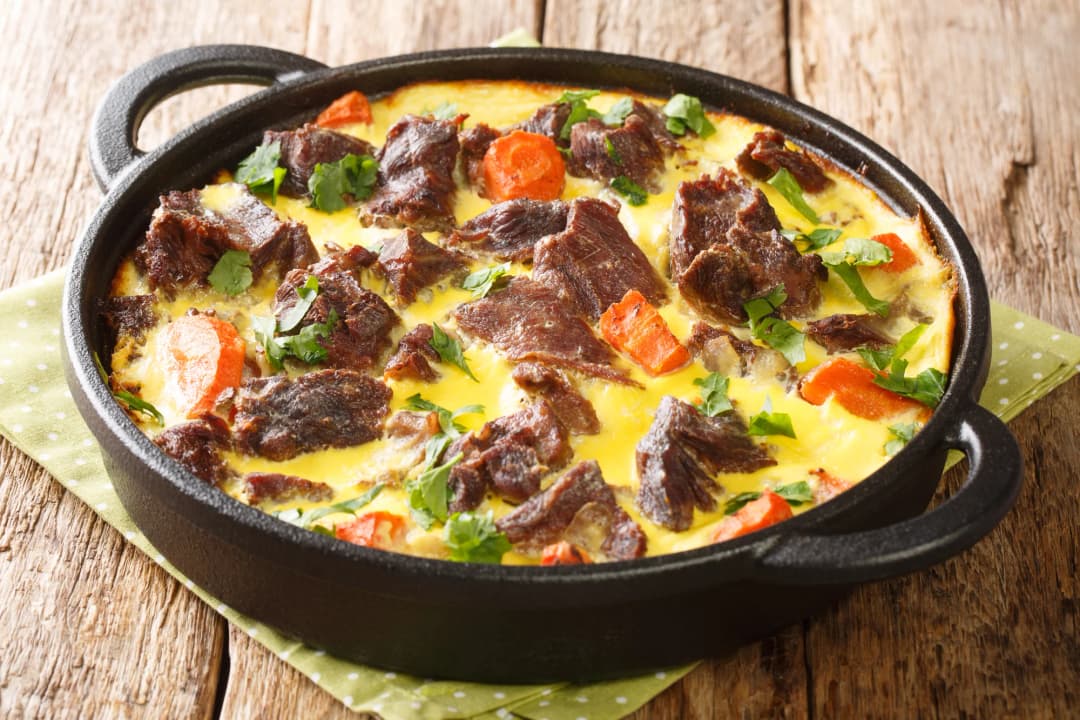 Escena de clase de cocina en una cocina montenegrina tradicional, participantes estirando masa para burek o preparando un plato local, con un instructor local demostrando técnica
