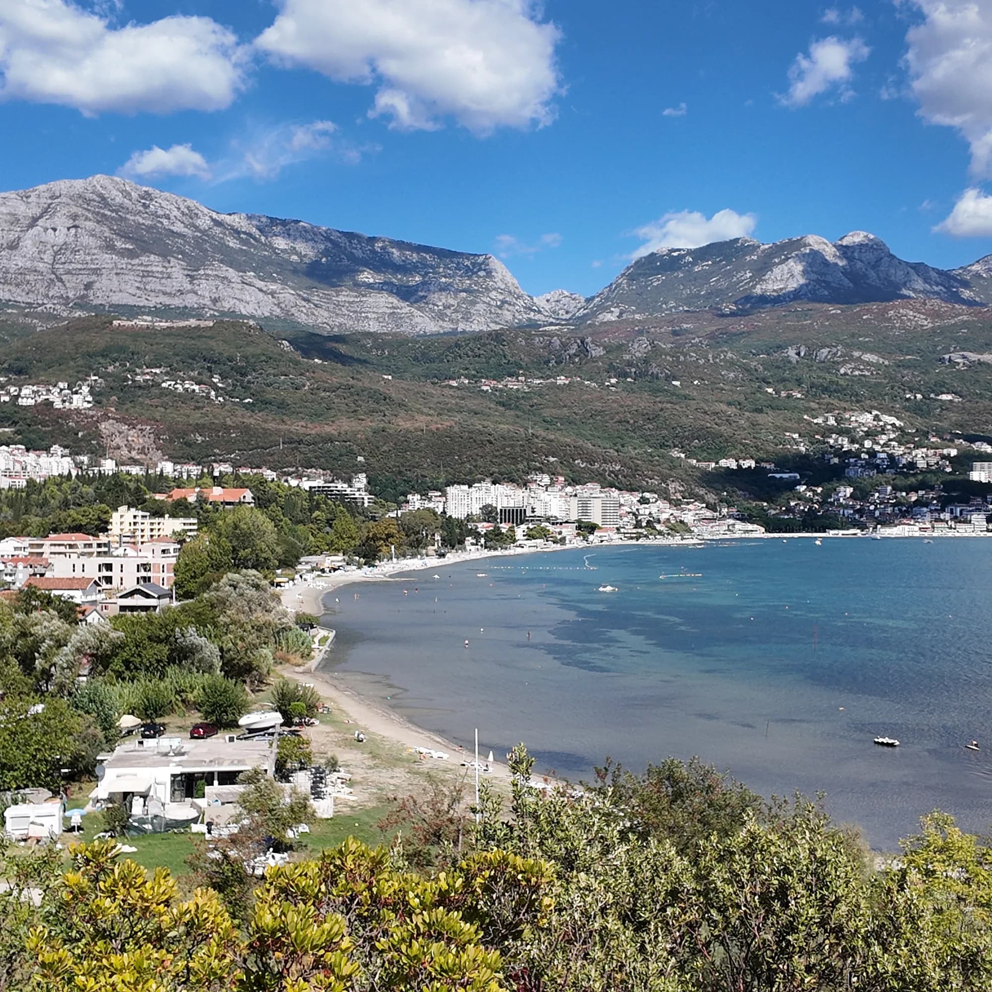 The curve of Igalo bay from the hill above Stara Banja, the strand and the Institute quarter strung along the shore, the mountains behind