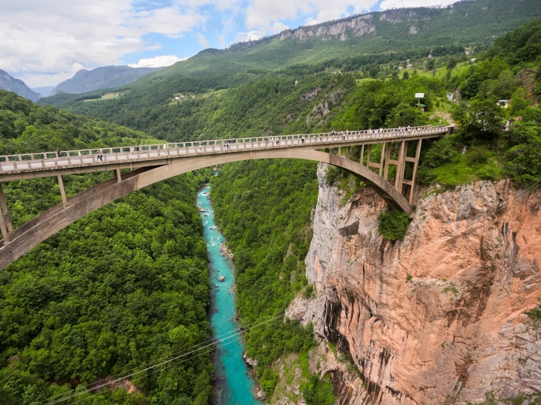 Pogled pri zalasku sunca s tvrđave San Giovanni prema dolje na kotorski Stari grad i Bokokotorski zaljev, koji prikazuje prepoznatljive narančaste krovove, obrambene zidine i zaljev koji se proteže u daljinu