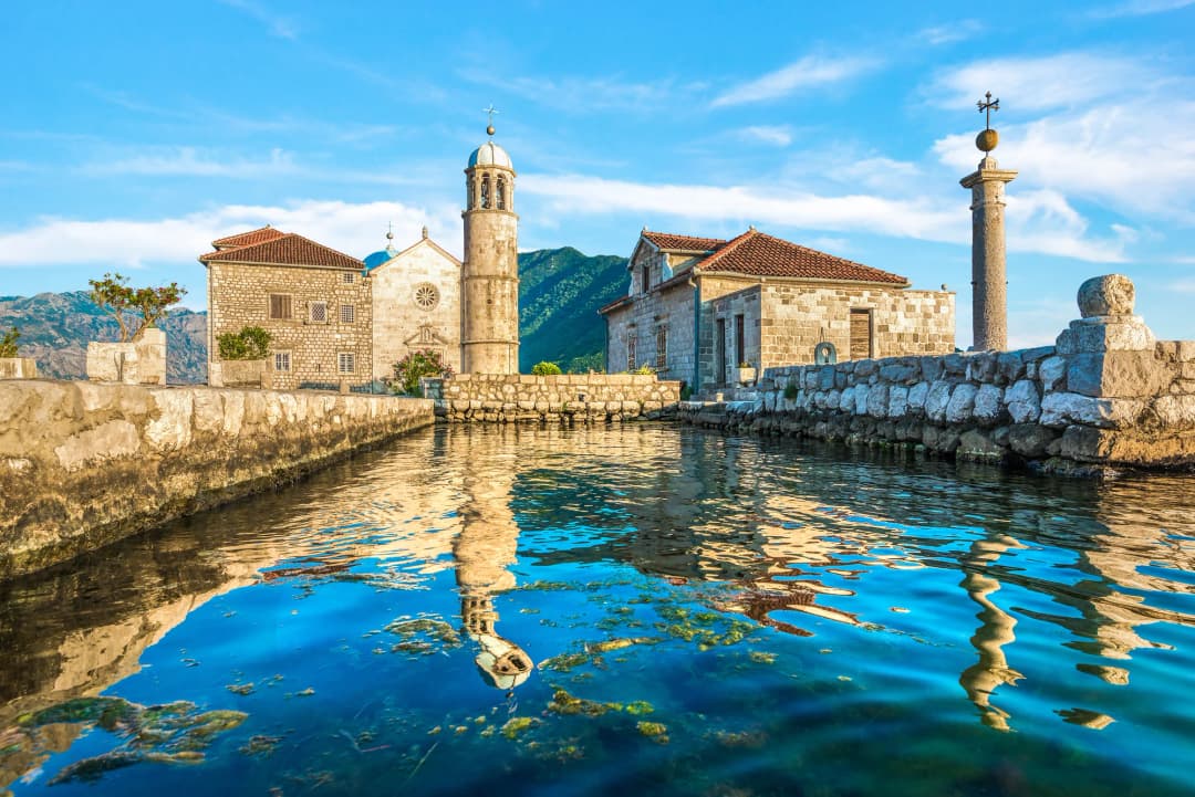 Crkvica Gospe od Škrpjela i njena obala viđene sa vode blizu Perasta