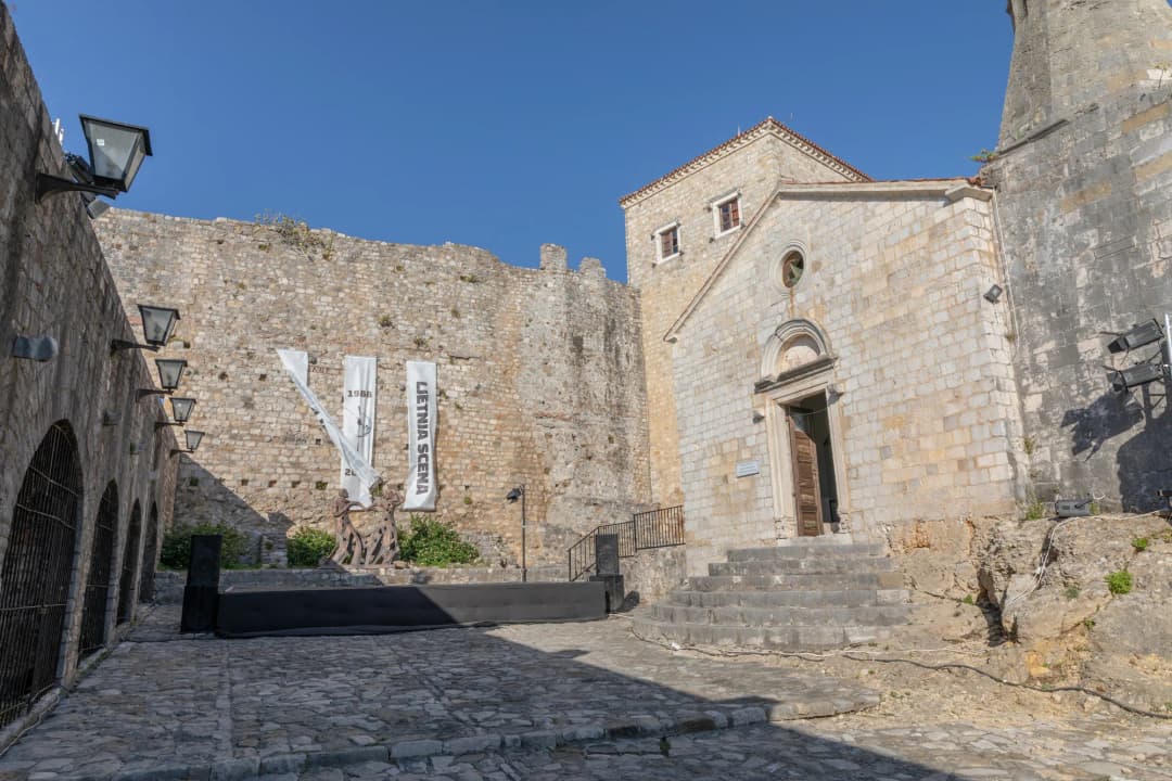 The square in front of the Ulcinj museum with fortress walls and summer stage banners