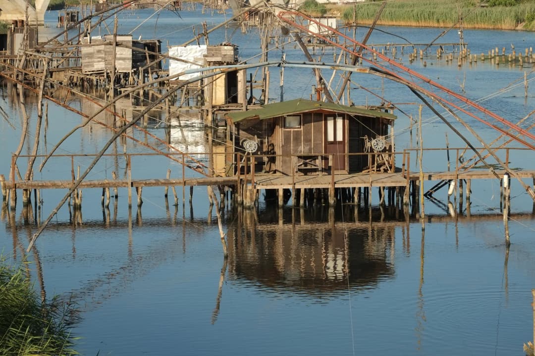 Close-up of a kalimera hut on stilts with counterweighted net booms over the canal