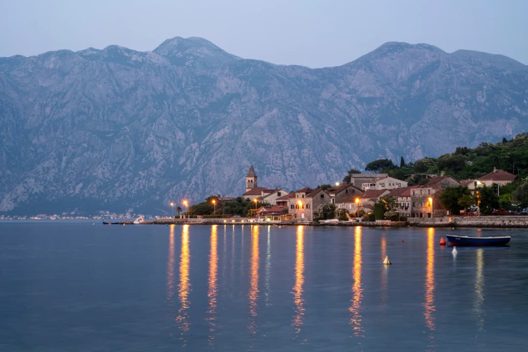 Prčanj waterfront at blue hour with the old parish church tower and lights on the water