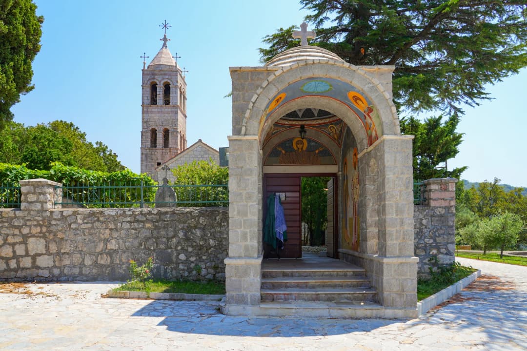 The frescoed entrance arch of Reževići monastery with the bell tower behind