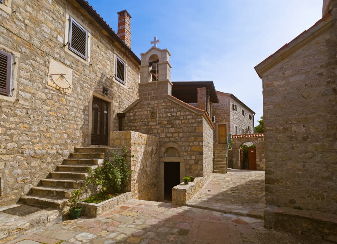 Stone courtyard of Reževići monastery with the small church and its bell-cote