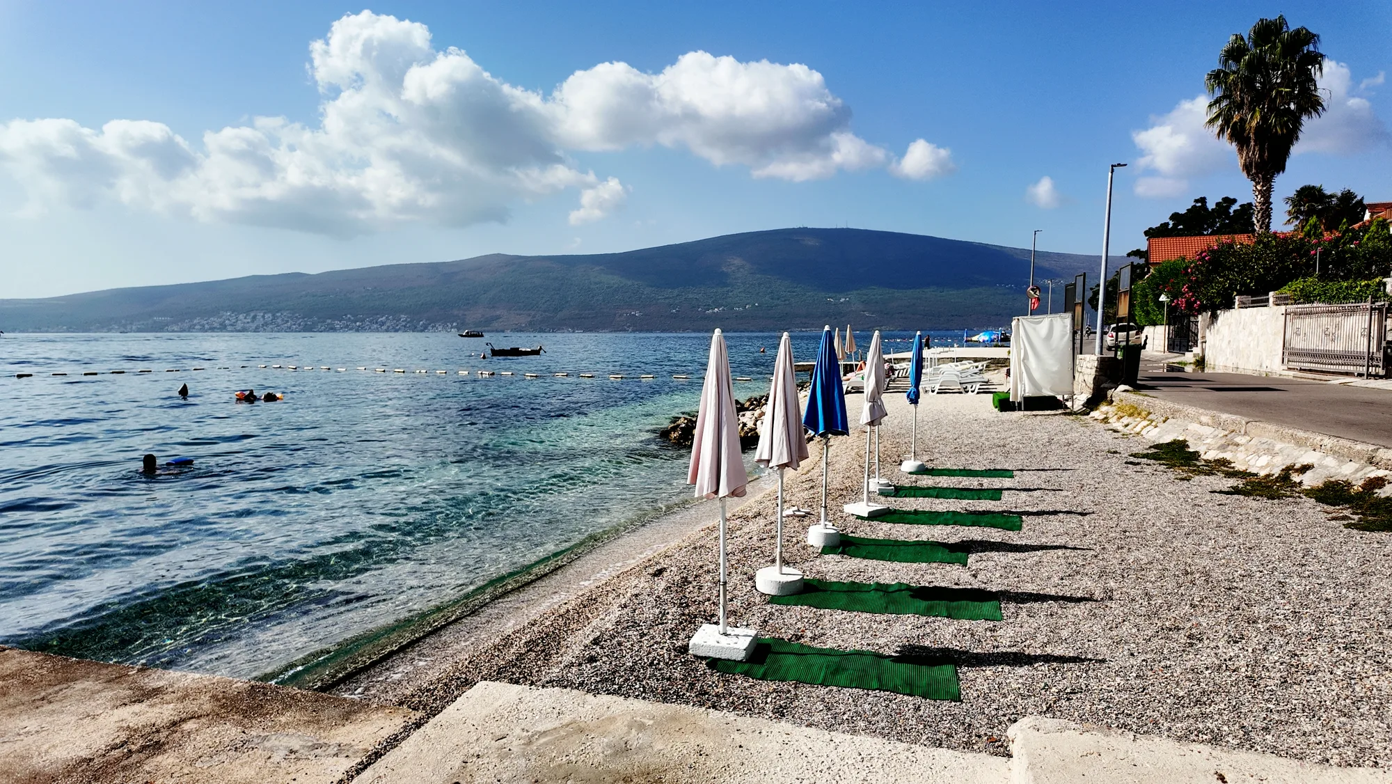 The pebble beach at Baošići with the far shore of the bay beyond