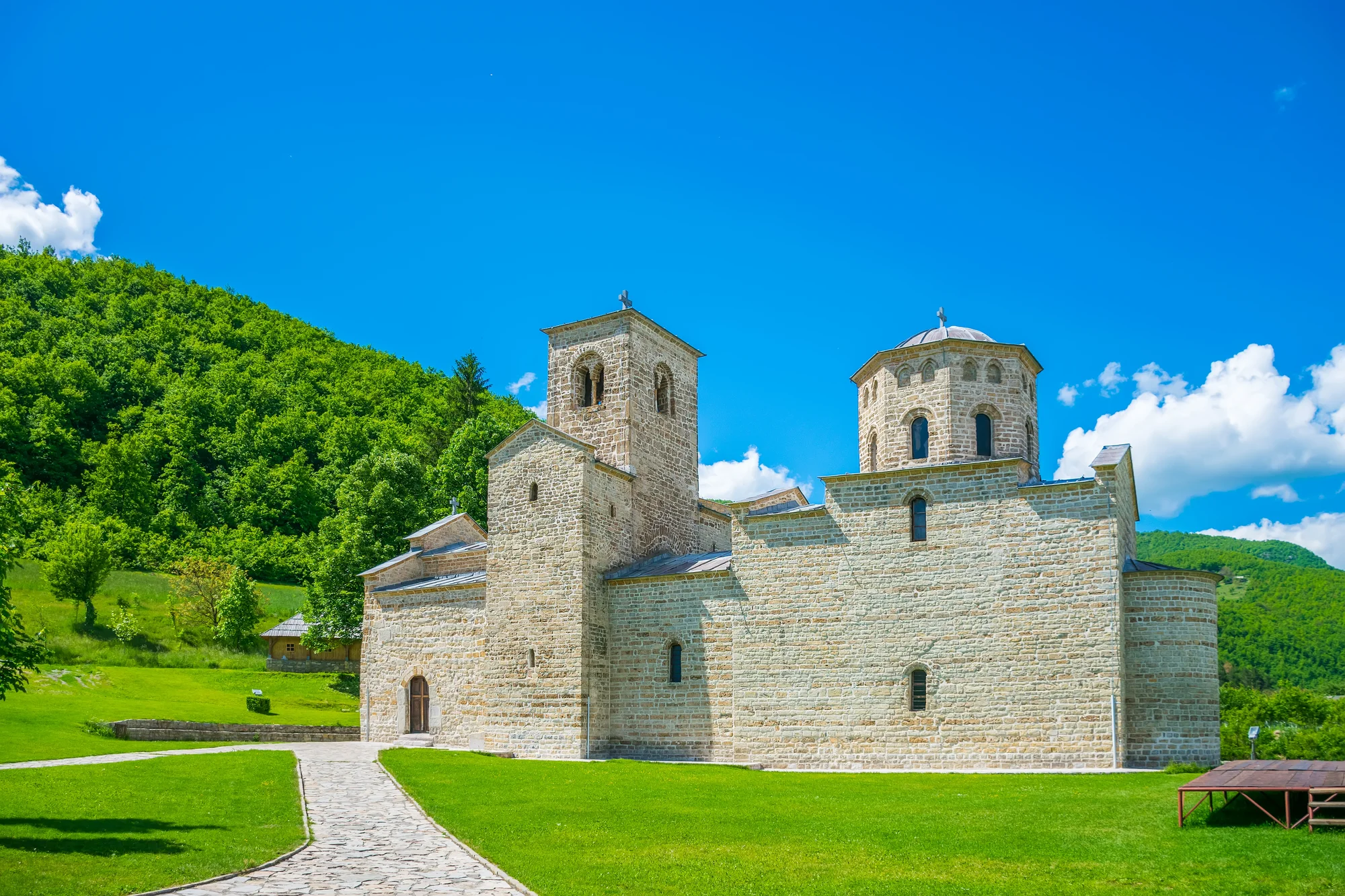 La iglesia de piedra de San Jorge en el monasterio de Đurđevi Stupovi, con su cúpula octogonal y su torre occidental sobre un césped recién segado