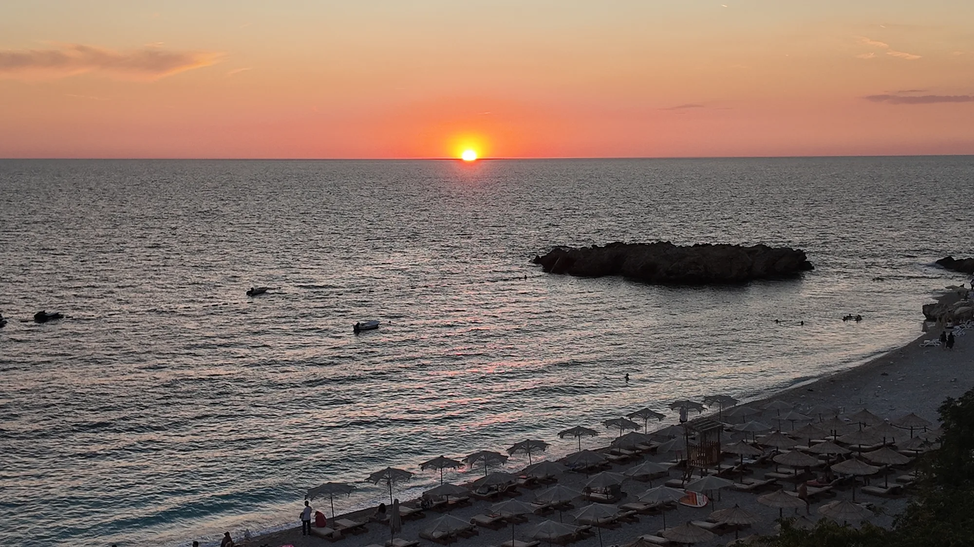 The sun meeting the Adriatic horizon above Veliki Kamen and the curve of the beach