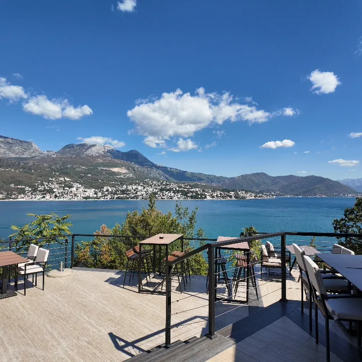 Herceg Novi oltre la baia, vista da una terrazza a Njivice: la città che sale lungo il suo pendio sotto l’Orjen e, in mezzo, l’acqua azzurra e piatta