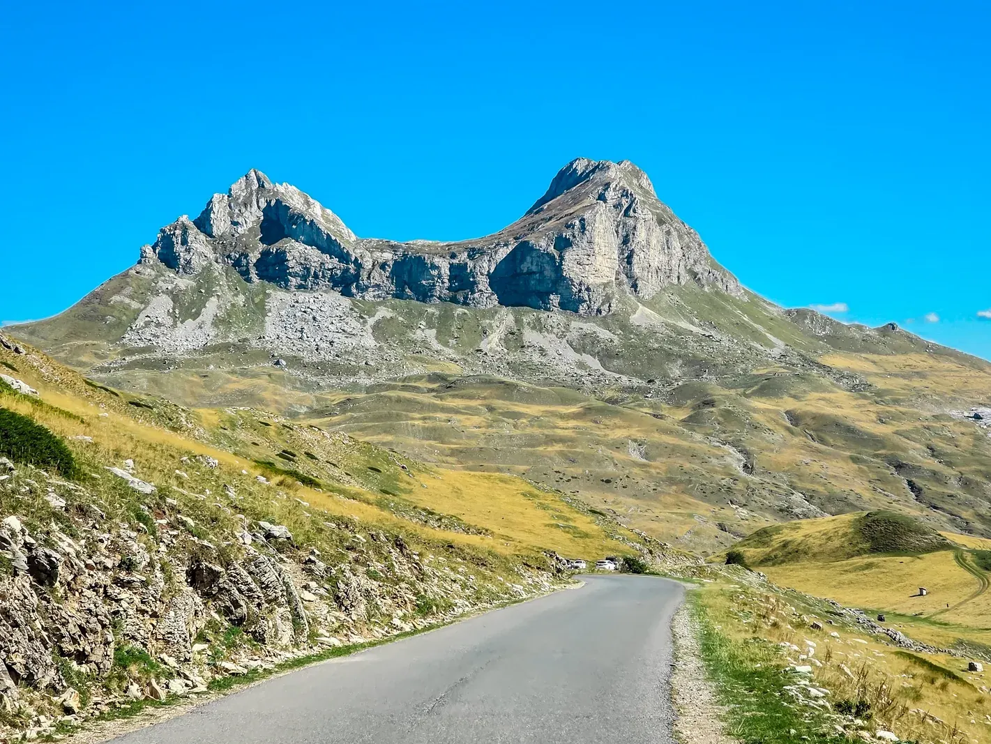 A winding mountain road with a safety barrier above the Bay of Kotor