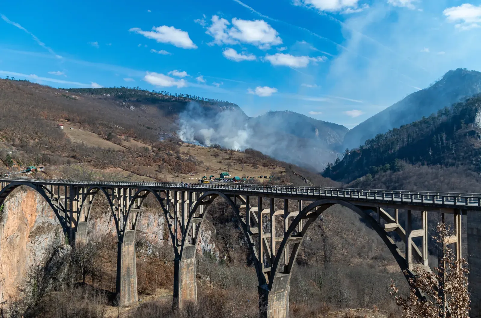 The Đurđevića Tara Bridge, a concrete arch carrying the road high over the Tara River canyon, the surrounding slopes bare in early spring
