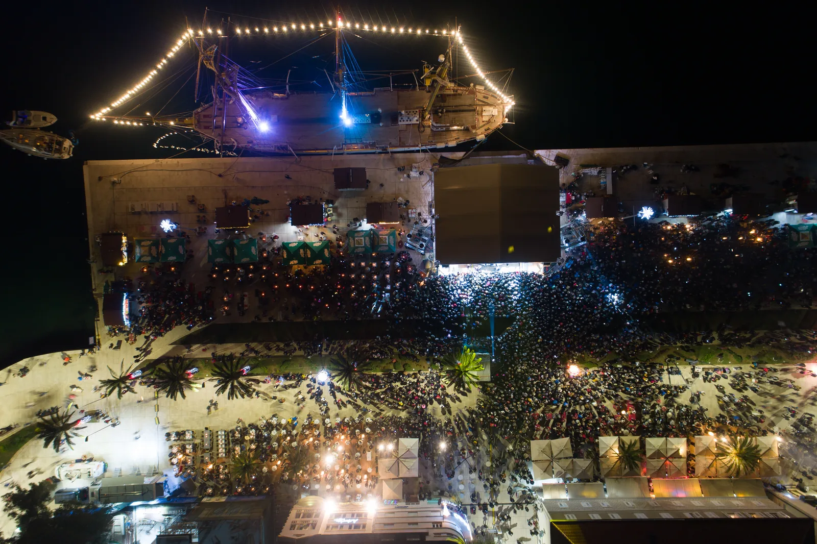 Aerial view of a packed nighttime festival crowd on the Montenegrin coast