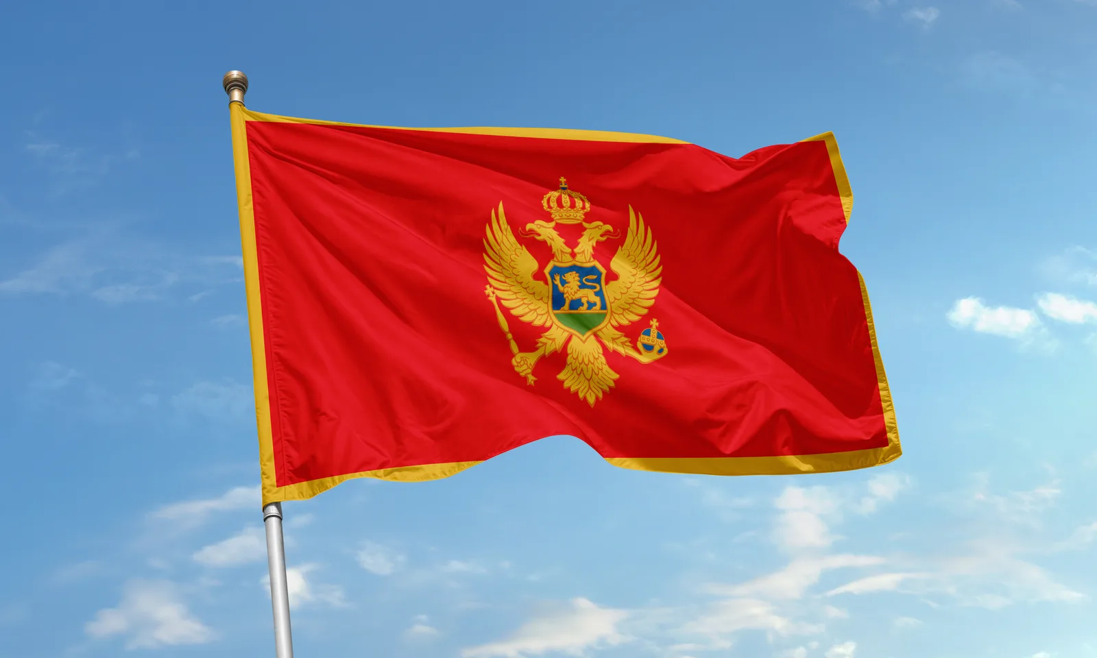 The flag of Montenegro flying against a blue sky