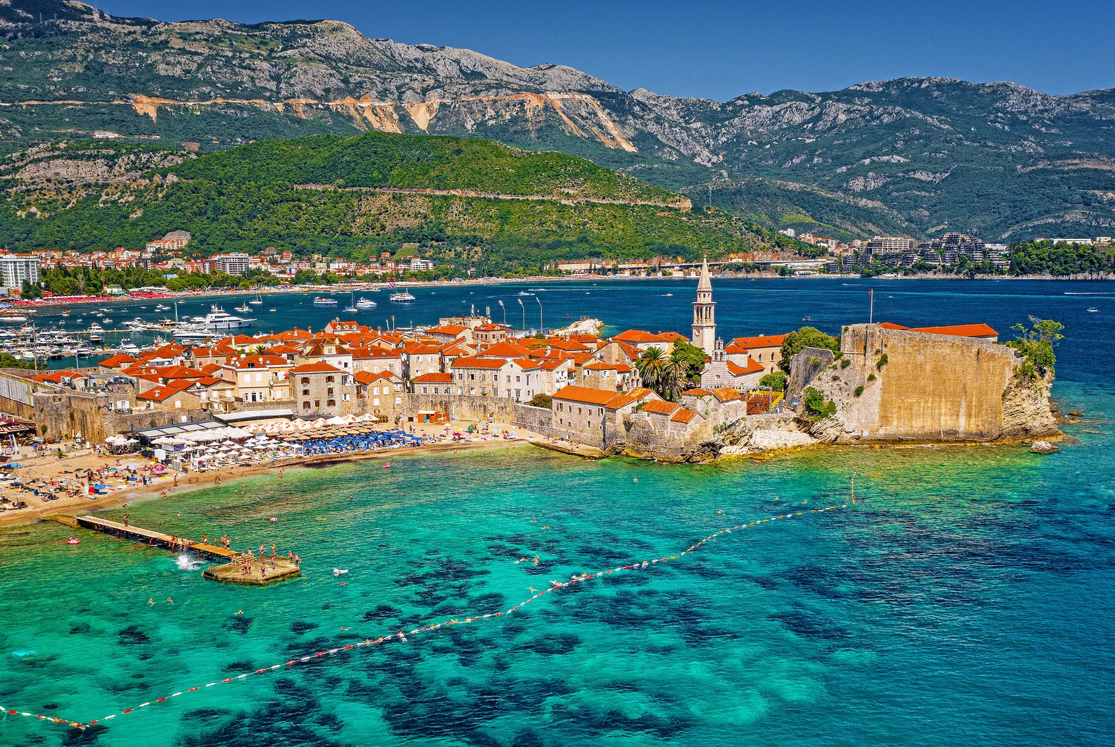 Vista aérea de la península de la Ciudad Vieja de Budva y la ciudadela rodeada de agua turquesa cristalina