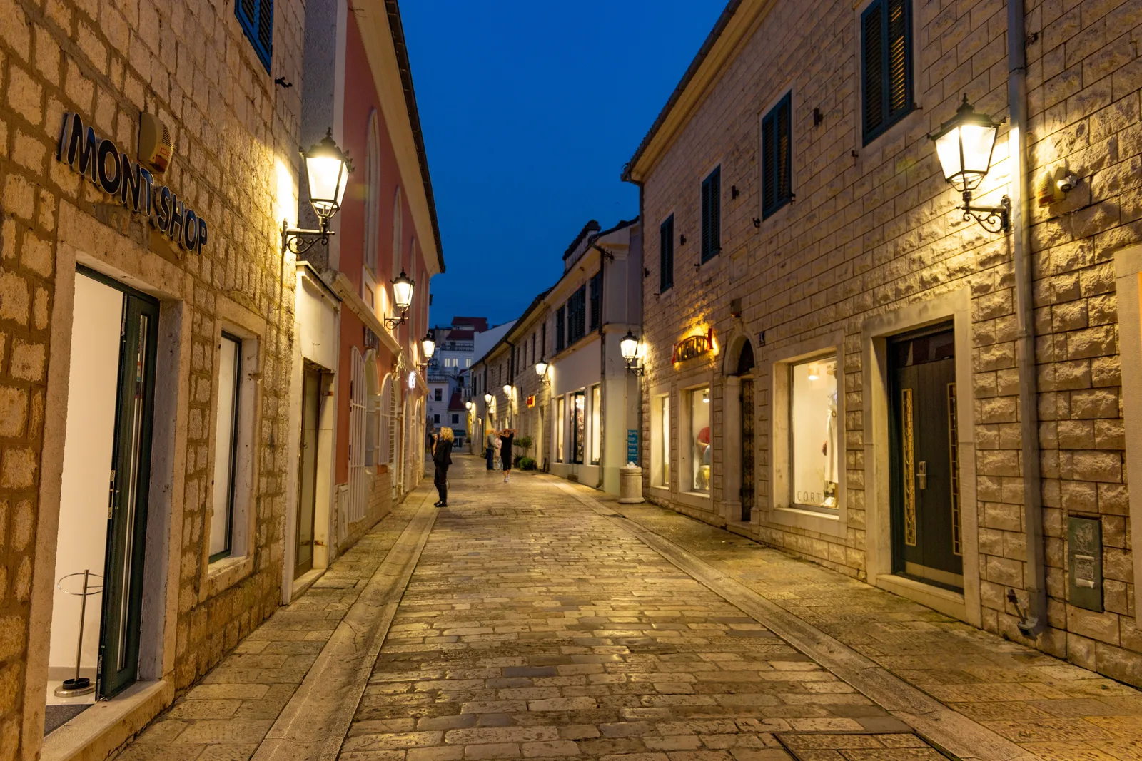 Una calle peatonal iluminada por faroles en el Casco Antiguo de Herceg Novi a la hora azul