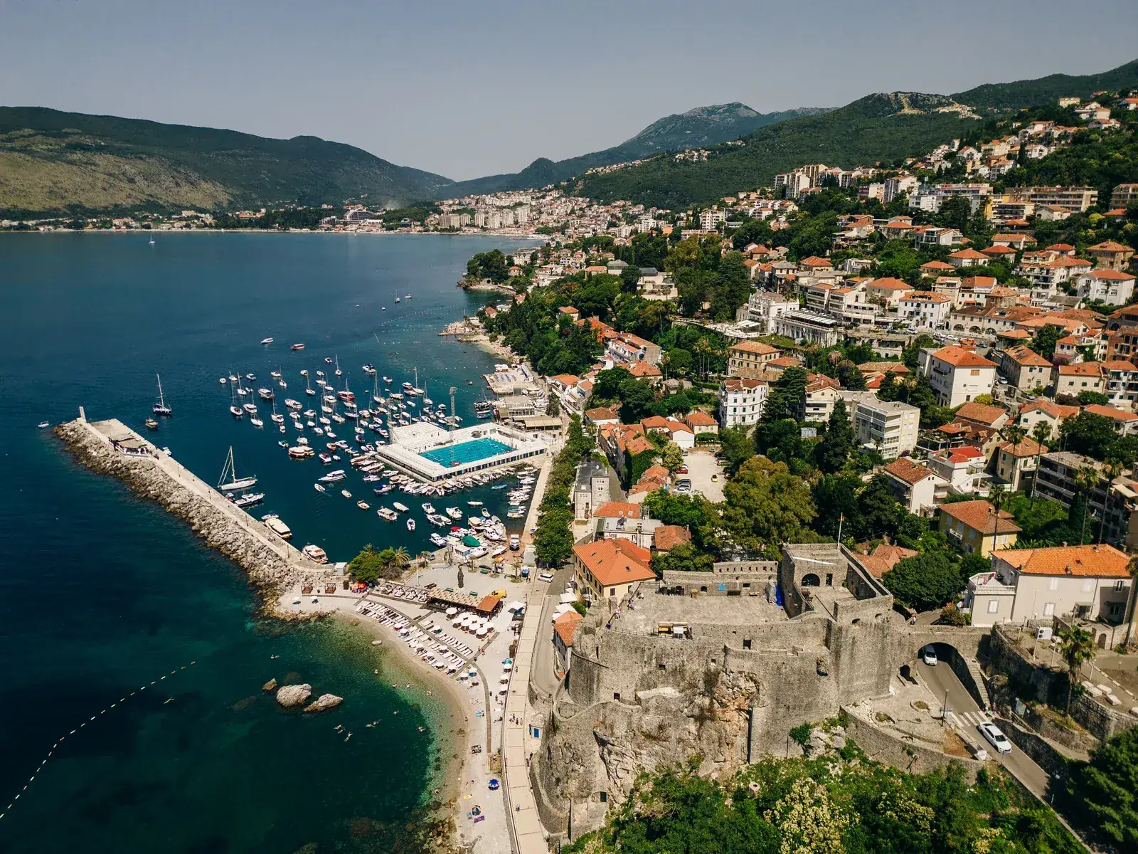 L'antico nucleo in pietra di Herceg Novi che si innalza sopra la baia, con i tetti di tegole e il campanile di una chiesa tra le terrazze.