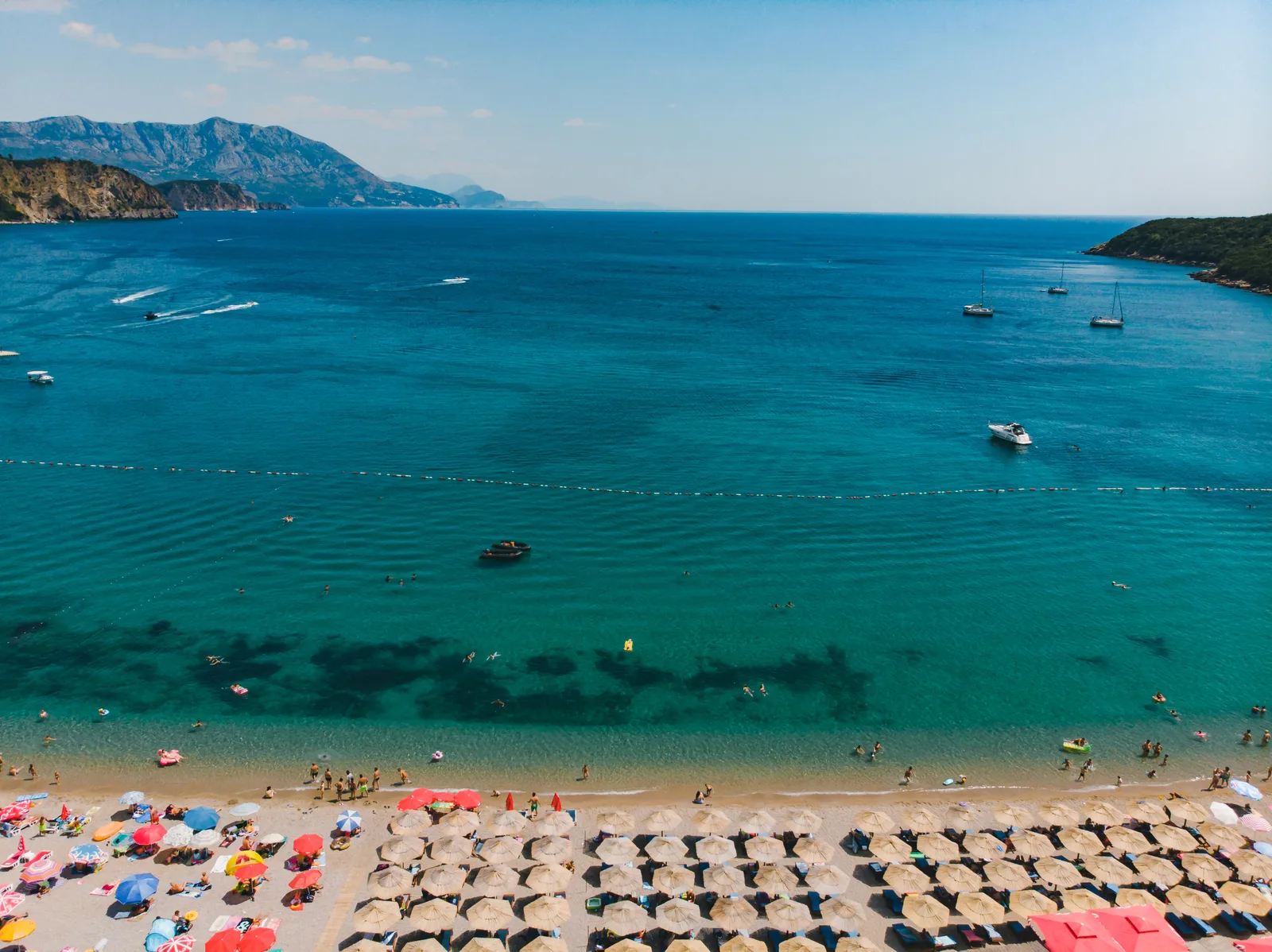 Brilliant turquoise shallows and boats off Jaz Beach near Budva from above