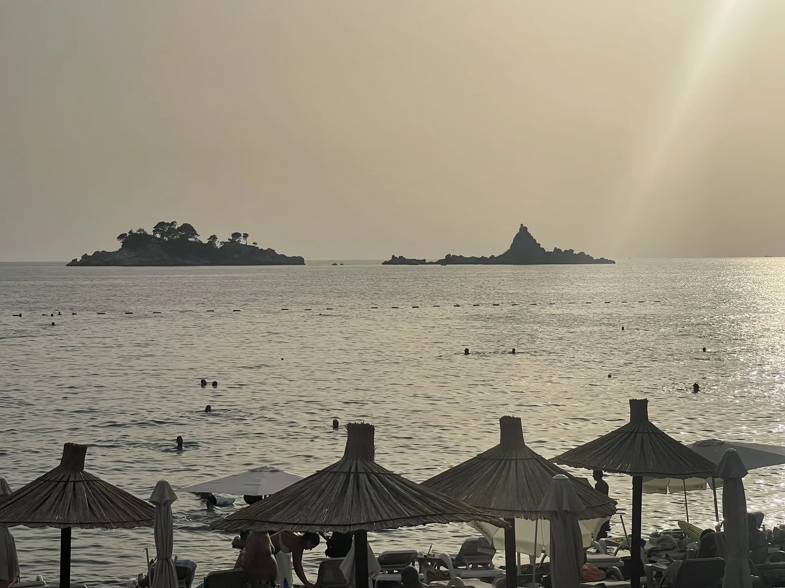 The Katič islets off Lučice at sunset, seen past thatched parasols