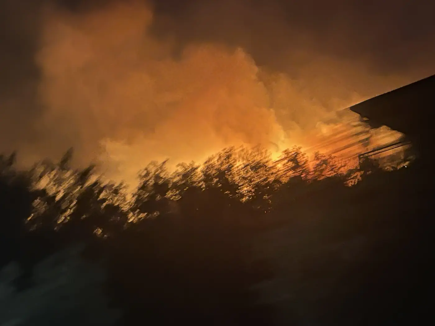 The flame front working along the crest of the ridge above Đenovići in the dark, smoke lit orange from beneath