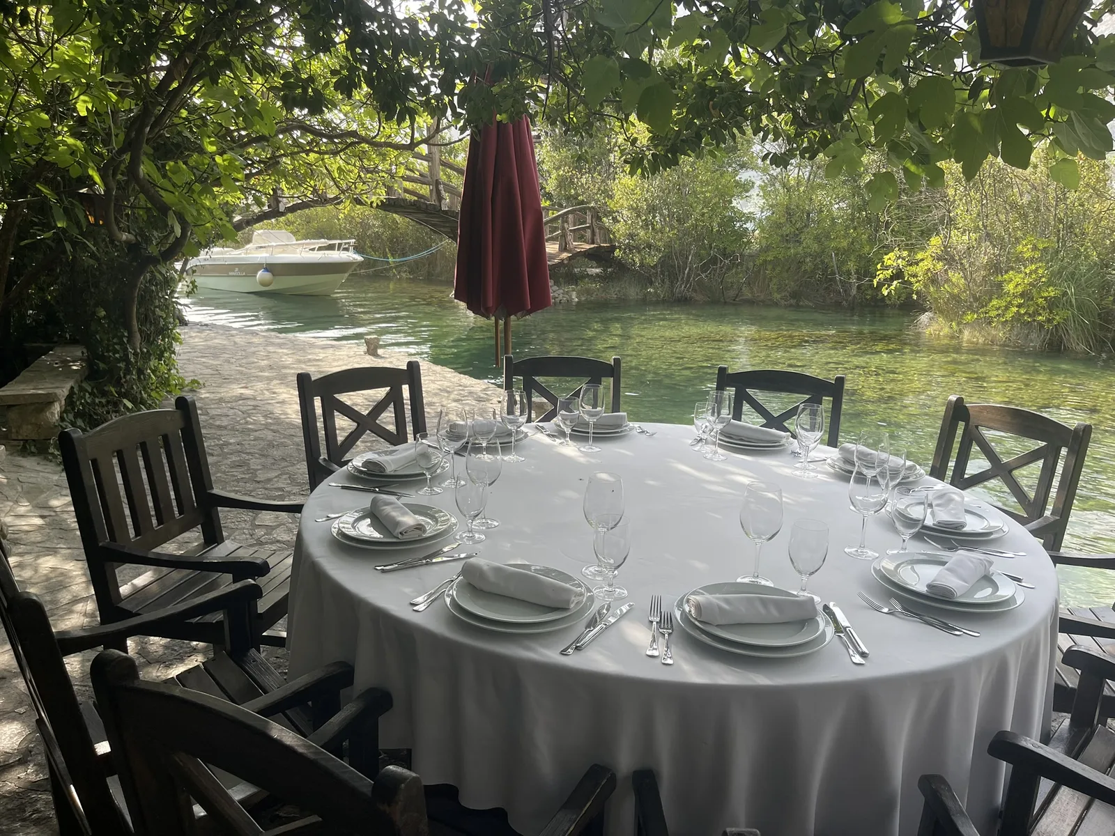 A table laid with white linen and glasses beside the mill stream at Stari Mlini