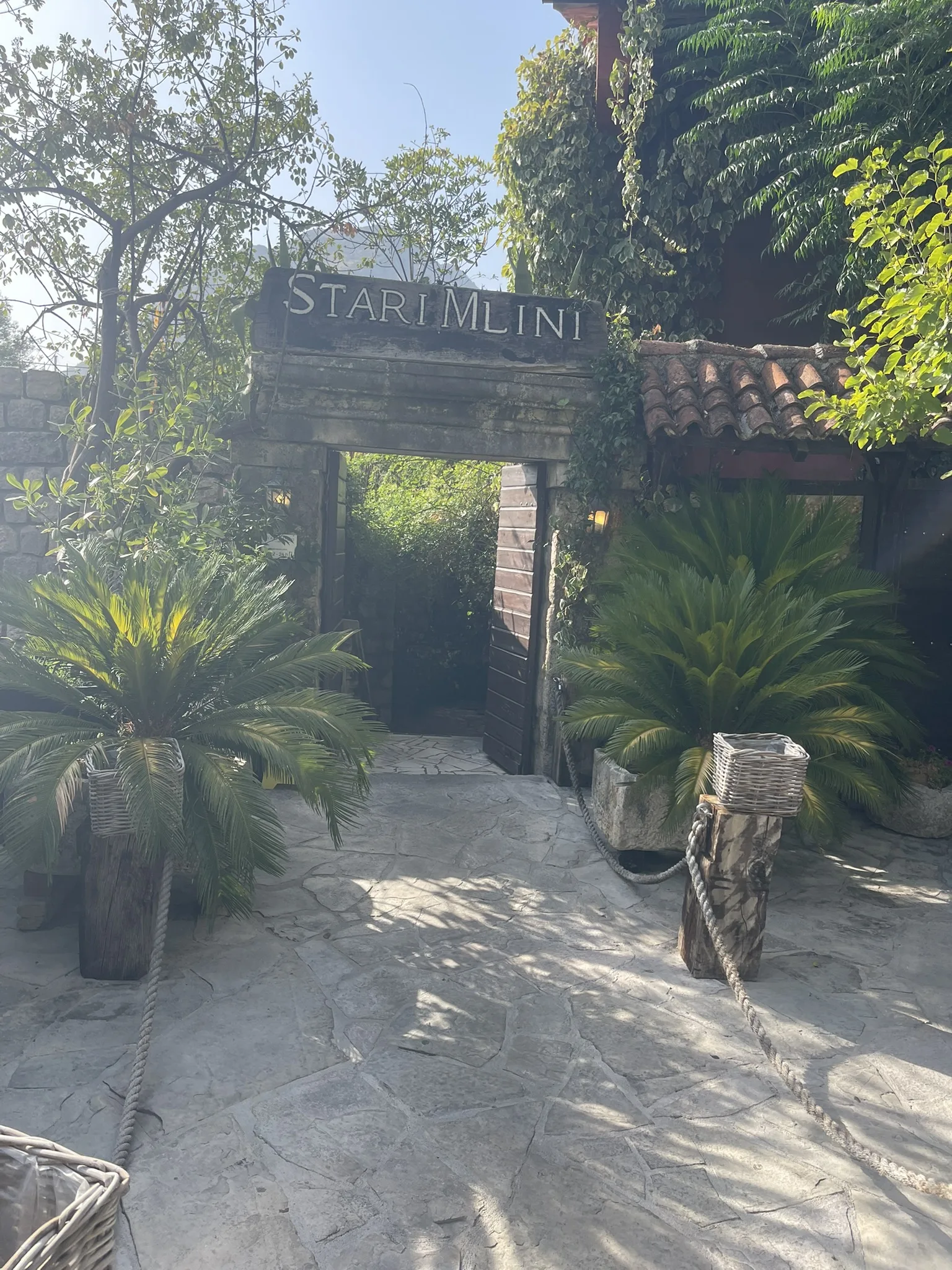 The timber and stone entrance to Stari Mlini under greenery