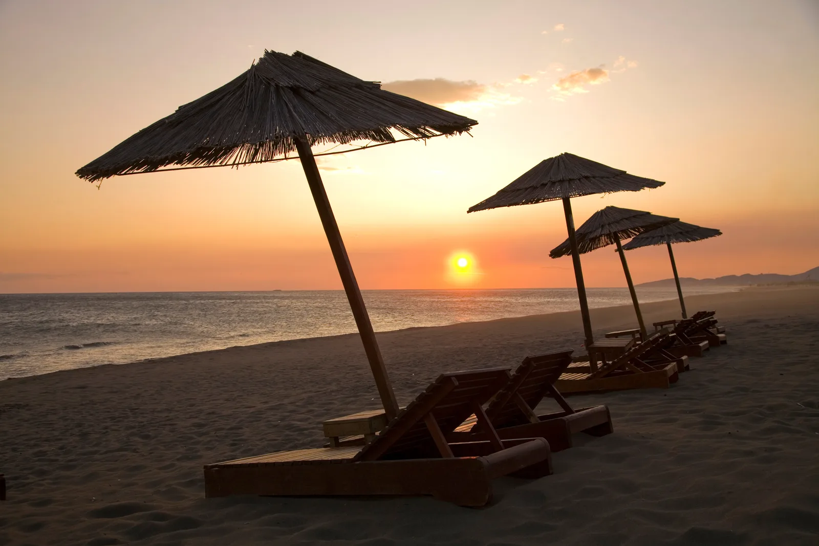 Sunset over Velika Plaza near Ulcinj, with straw umbrellas and loungers on the long sandy beach