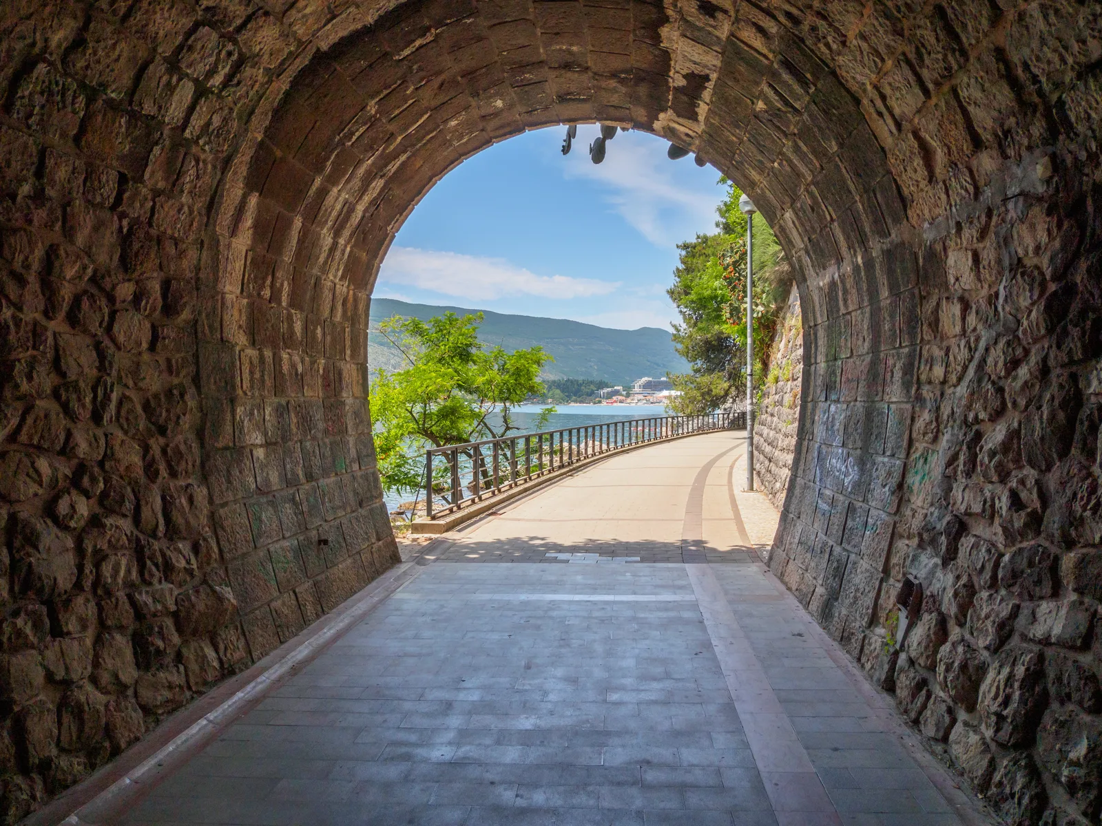 A stone tunnel opening onto the seaside promenade and the Bay of Kotor at Herceg Novi