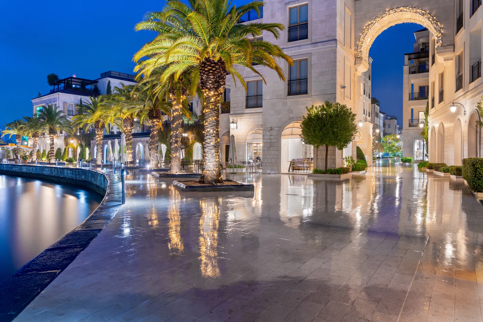 The Porto Montenegro promenade in Tivat at blue hour, with lit palms and reflective paving