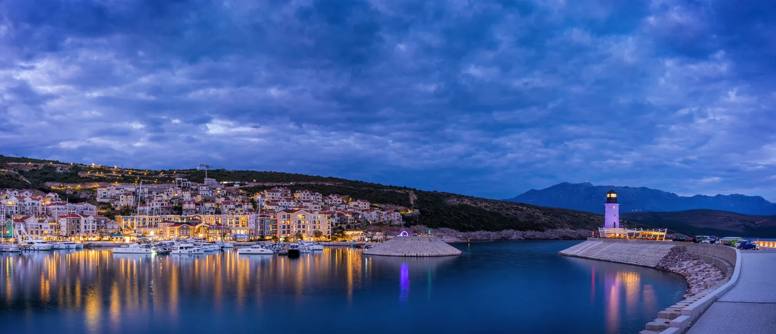 Marina village on the Luštica peninsula at dusk with a lighthouse and moored yachts