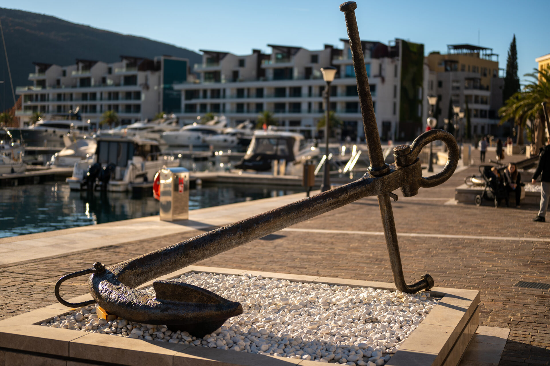 The modern Portonovi marina plaza with a large anchor monument and contemporary buildings
