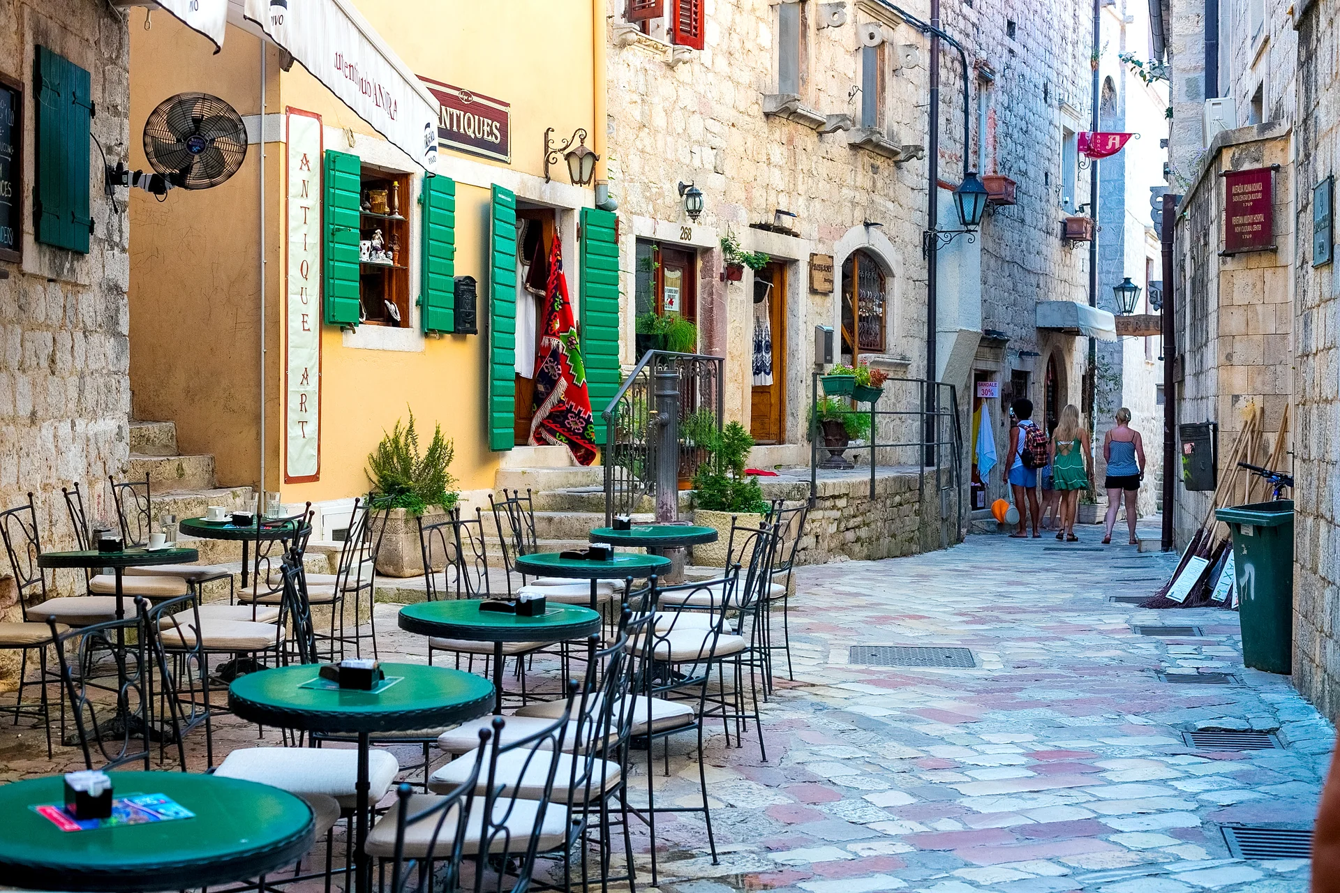 Kafanski restoran na otvorenom u Starom gradu Kotor sa stolovima postavljenim pod žutim suncobranima